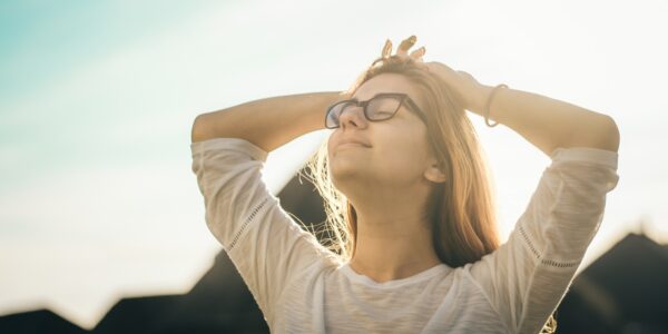 woman in white crew-neck T-shirt holding her head